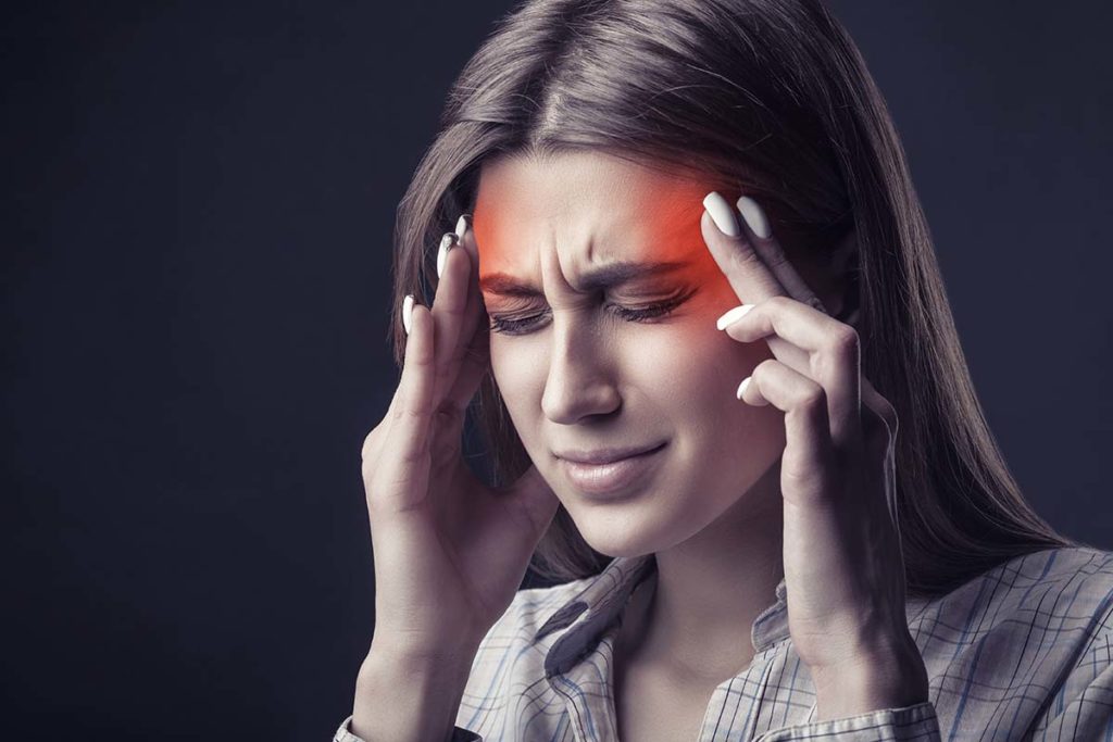 a person rubs their inflamed temples possibly struggling with the interaction of alcohol and the brain